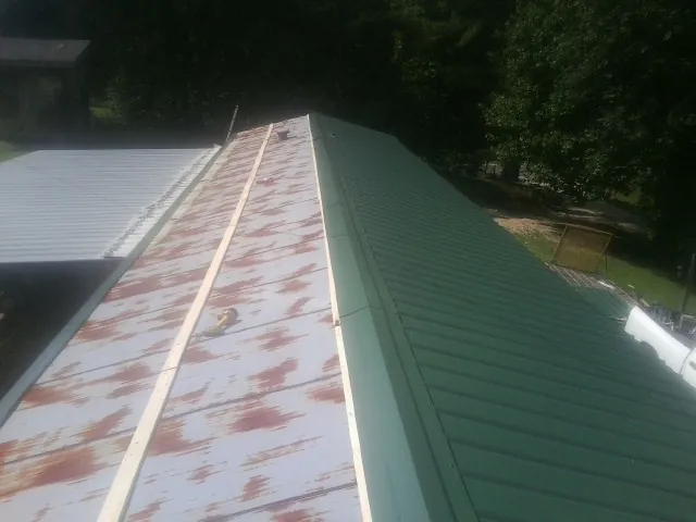 Old rusted panels beside newly installed green metal roofing — Wind Damage Roof Repair by Roofing Brothers in Cashiers