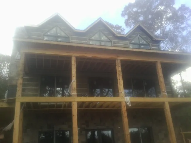 Dormers and porch framing on a large log home under construction — Roof Coating work by our crew in Cashiers