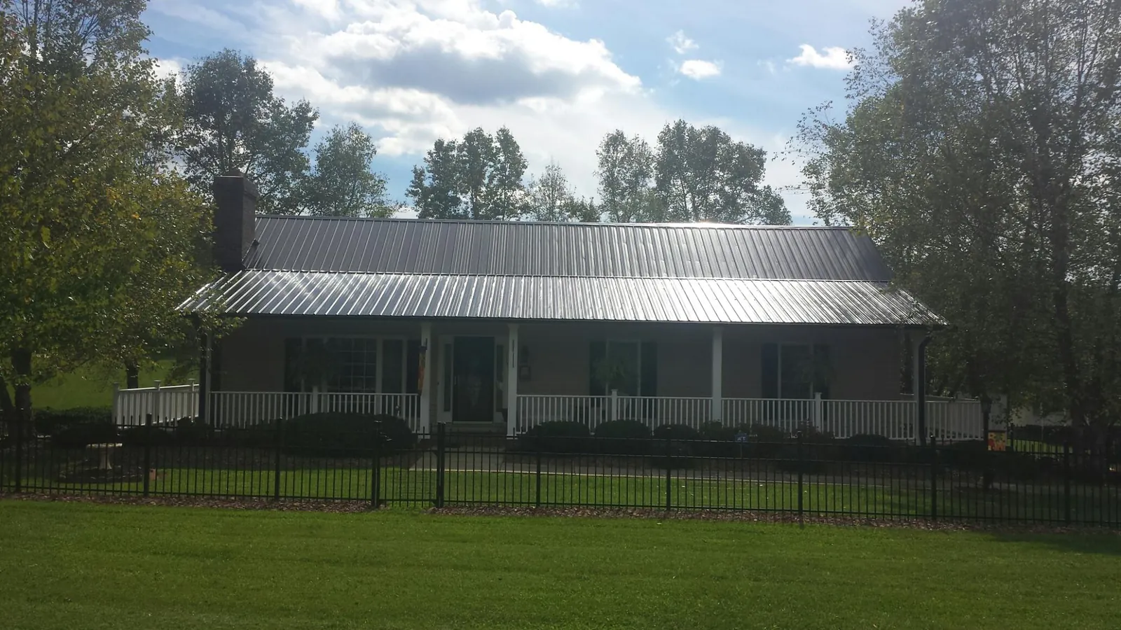 Gray metal roof on a brick ranch with a full width front porch — Gutter Guard Installation work by our crew in Cashiers