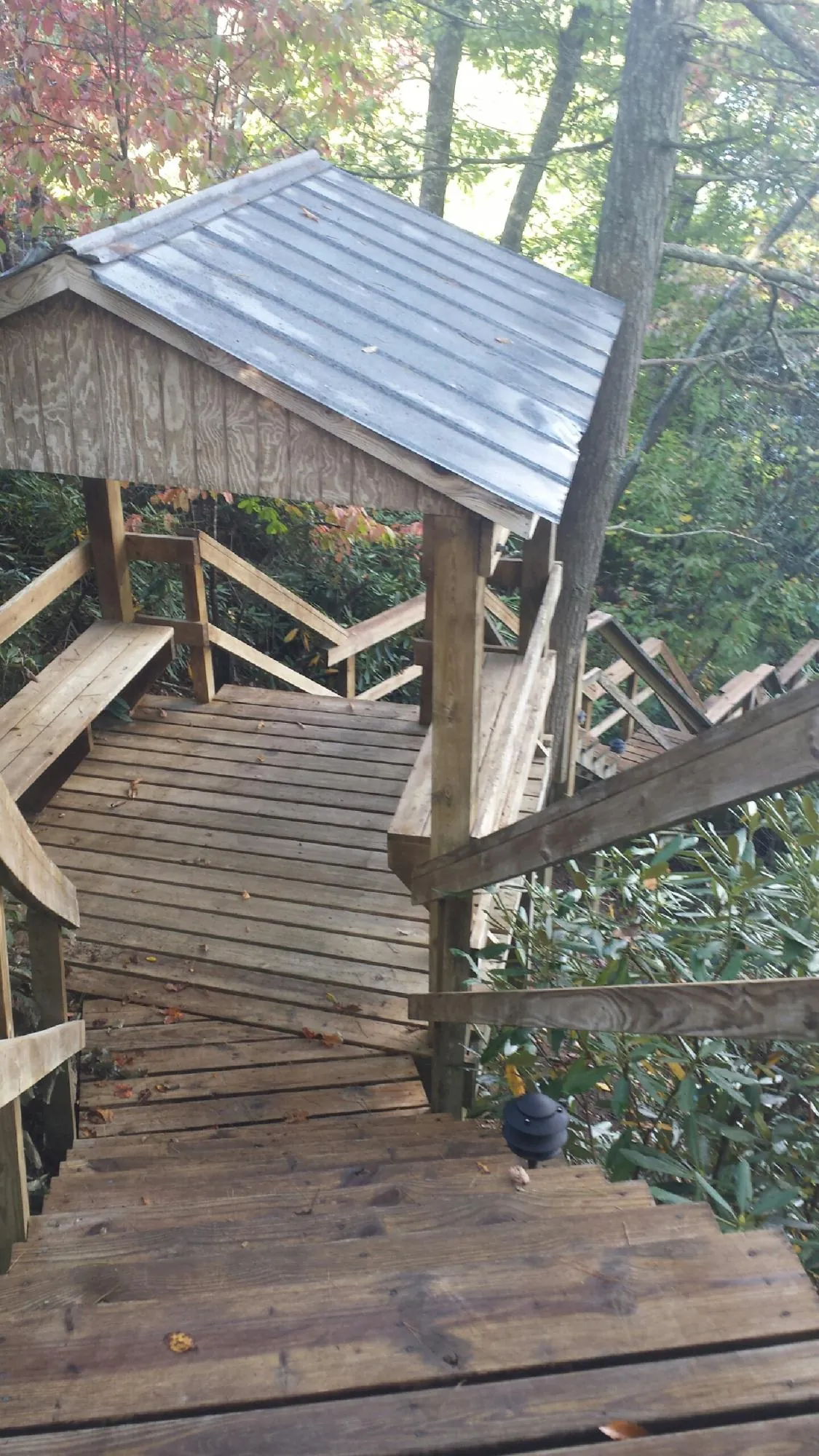 Metal roofed shelter over wooden steps on a wooded walkway — Skylight Repair & Installation work by our crew in Cashiers