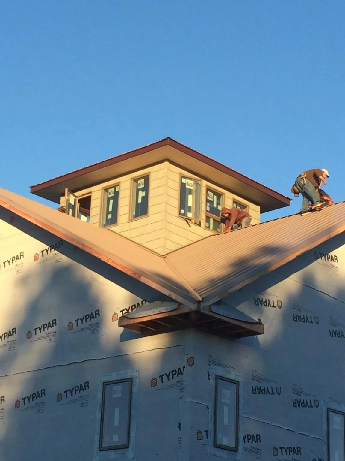 Roofers working around a rooftop cupola on a new metal roof at sunset — Roof Waterproofing in Cashiers by Roofing Brothers